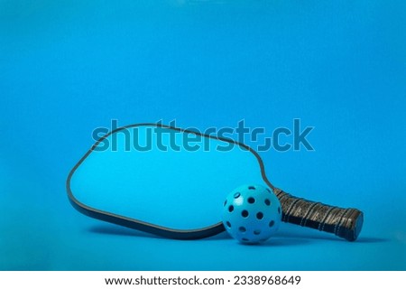 Pickleball in Blue...Blue Pickleball paddle with blue Pickleball on a blue background. Royalty-Free Stock Photo #2338968649