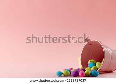 Image of multi coloured easter eggs, pink bucket with copy space on pink background. Easter, religion, tradition and celebration concept.
