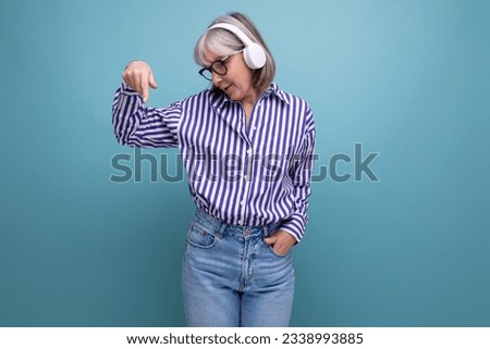 happy woman pensioner with gray hair with headphones on a bright studio background