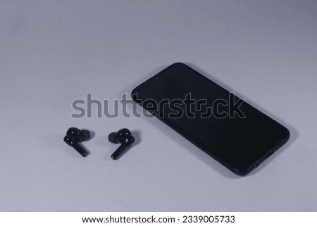 A black smartphone with wireless headphones or bluetooth earbuds on a white background. For listening music or audio format file