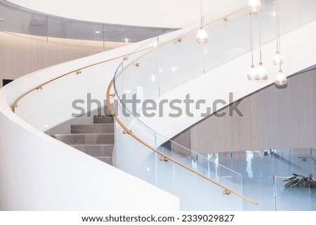 White spiral staircase with tempered glass railings and brushed gold handrail Royalty-Free Stock Photo #2339029827