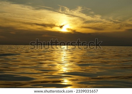 Golden shine of sea waves below dramatic sky during sea summer sunset