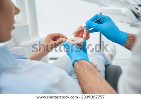 Dental technician using 3d teeth model to show to client problem places Royalty-Free Stock Photo #2339062757