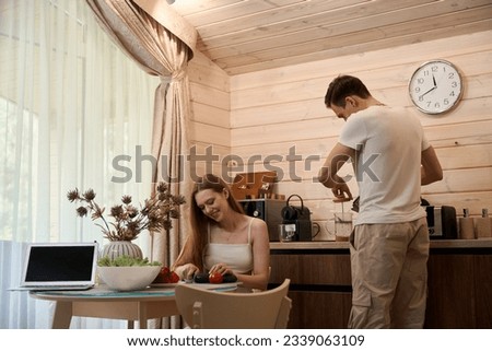 Young man makes tea, woman cuts vegetables for a salad