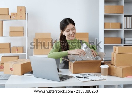 Young small business owner SME packing the product inside box, preparing for the customer. Royalty-Free Stock Photo #2339080253