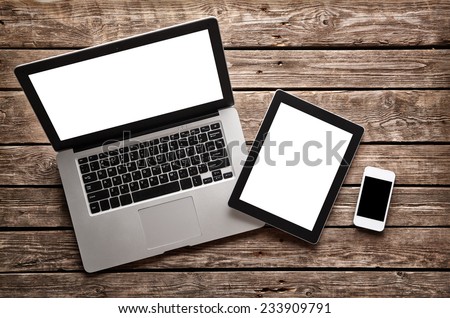 Open laptop with digital tablet and white smartphone. All with isolated screen on old wooden desk. Royalty-Free Stock Photo #233909791