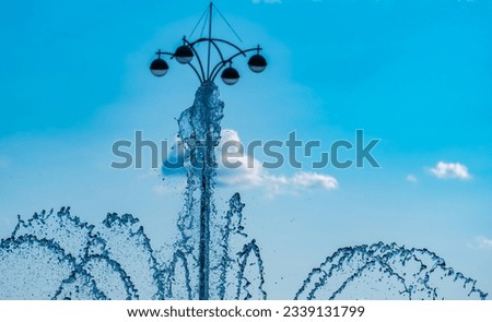 Transparent water jets from a fountain against the sky.