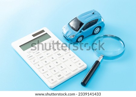 Car, calculator and magnifying glass on blue background. Royalty-Free Stock Photo #2339141433