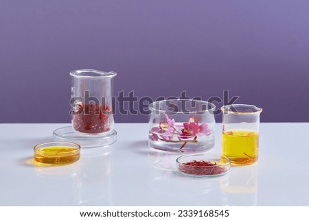 Purple flowers, saffron and yellow liquid contained inside some laboratory glassware on purple background. Saffron may improve mood and treat depressive symptoms