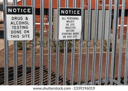 black and white Notice, Drug and Alcohol Testing Done on This Site and All Personnel Must Be Site Inducted signs on the exterior of a workplace boundary fence Royalty-Free Stock Photo #2339196019