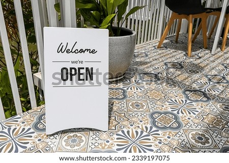 Text on vintage white sign " welcome we'are Open" in cafe.