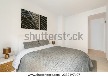 Stylish bedroom with a double bed and light walls and stylish bedding and a picture on the wall. Concept of minimalistic modern design in an apartment for a young couple