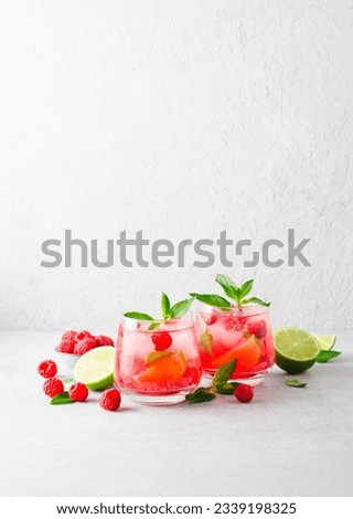 Refreshing Cold Cocktail or Mocktail with Berries and Lime, Raspberry Lemonade on Bright Background Royalty-Free Stock Photo #2339198325