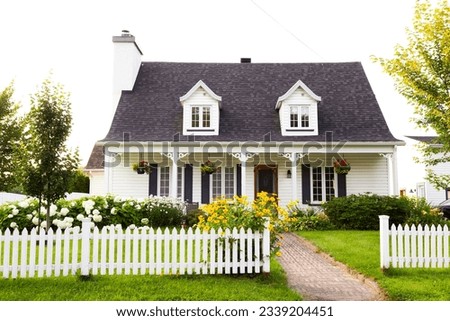 Pretty petite ancestral neoclassical white clapboard house with shingled roof and picket fence in the Ste-Foy area, Quebec City, Quebec, Canada Royalty-Free Stock Photo #2339204451