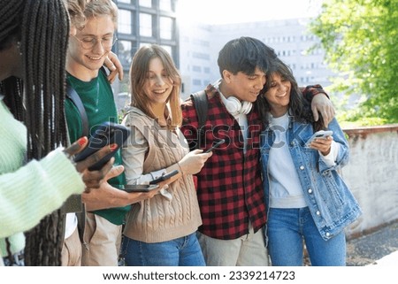 Multicultural University Students Interacting in Courtyard - Diverse students standing, interacting, hugging, with mobiles. Royalty-Free Stock Photo #2339214723