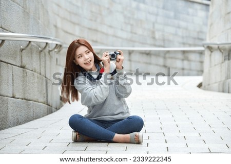 a young woman sitting in the street taking pictures with a camera while traveling