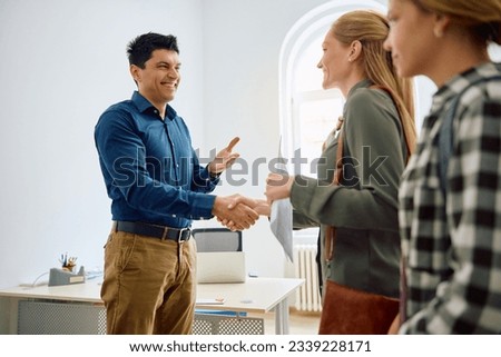 Happy high school principal greeting mother and her teenage daughter at his office. Royalty-Free Stock Photo #2339228171