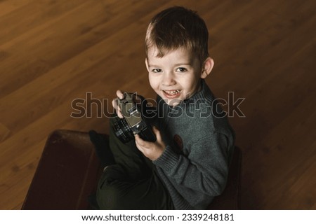 world photography day. a boy holds a retro camera in his hands while sitting on the floor