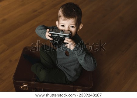 world photography day. a boy holds a retro camera in his hands while sitting on the floor