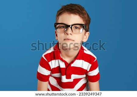 Closeup portrait of young tired overwhelmed nerdy boy, stressed, wearing red striped polo shirt and eyeglasses isolated over blue background. Negative human emotions, facial expressions, feelings