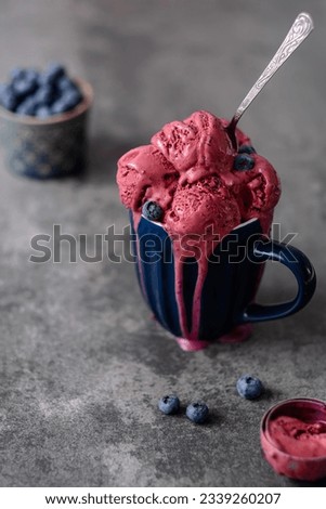 Homemade vegan ice cream scoops melting served in blue mug with spoon on a concrete background. Healthy frozen dessert. Vegan food concept. Summer and Sweet menu. side view. High quality photo