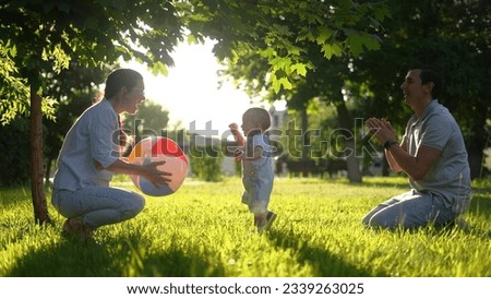 people in the park. happy family in park. mom dad and baby play ball at sunset in the park. happy family a kid dream concept. baby toddler plays ball with parents at sunset nature