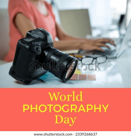 World photography day text on pink with camera on desk of biracial woman using laptop. Global celebration of photography campaign, digitally generated image.