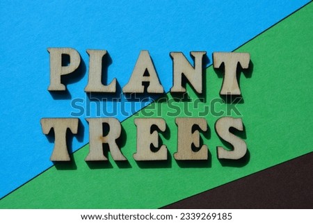 Plant Trees, words in wooden alphabet letters isolated on blue, green and brown background as banner headline