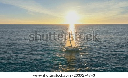Aerial drone ultra wide photo of beautiful sailboat cruising deep blue open ocean. Sailing. Sailboat with white sails, blue sky and rippled sea background. Summer holidays. 