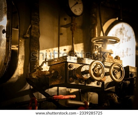 Trains – The cockpit of an old train. Warm light shines into the driver's cab of the old locomotive. There are no people to be seen. The machine stands still. Royalty-Free Stock Photo #2339285725