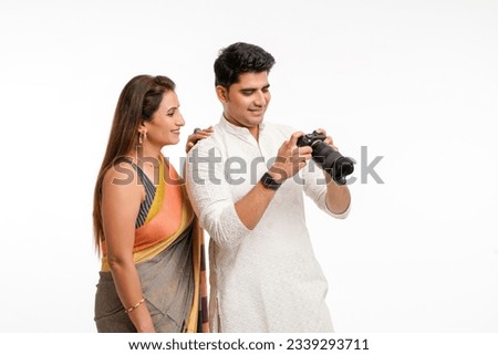 Indian couple using camera on white background