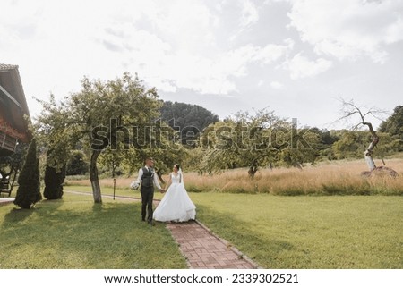 A beautiful wedding, a beautiful couple in love, walking on the background of a green garden with tall green trees. High quality photo