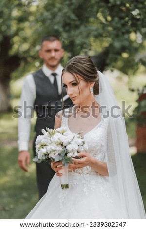 Beautiful wedding, a beautiful couple in love, on the background of a green garden, the bride in the foreground. High quality photo