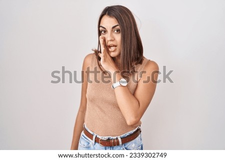 Young hispanic woman standing over white background hand on mouth telling secret rumor, whispering malicious talk conversation  Royalty-Free Stock Photo #2339302749