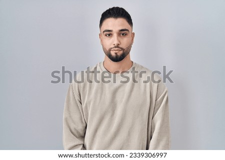 Young handsome man standing over isolated background relaxed with serious expression on face. simple and natural looking at the camera.  Royalty-Free Stock Photo #2339306997