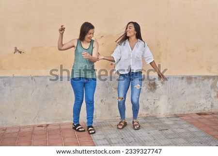 Two women mother and daughter smiling confident dancing at street