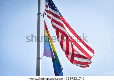 LGBTQIA flag and United States of America flags seen together hoisted on a pole Royalty-Free Stock Photo #2339331741