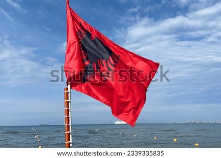 The red silk Albania Flag waves on blue sky background,  flag on a flagpole, closeup