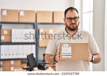 Plus size hispanic man with beard working at small business ecommerce skeptic and nervous, frowning upset because of problem. negative person. 
