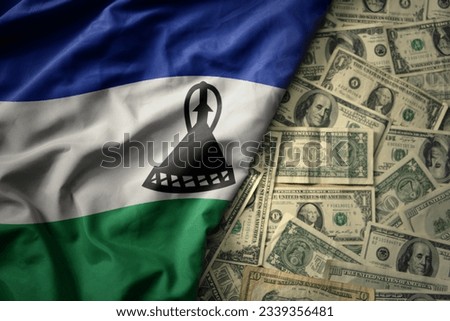 big colorful waving national flag of lesotho on a american dollar money background. finance concept