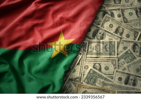 big colorful waving national flag of burkina faso on a american dollar money background. finance concept