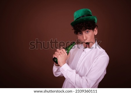 Young funny guy with a beer posing on a brown background. Irish holiday.