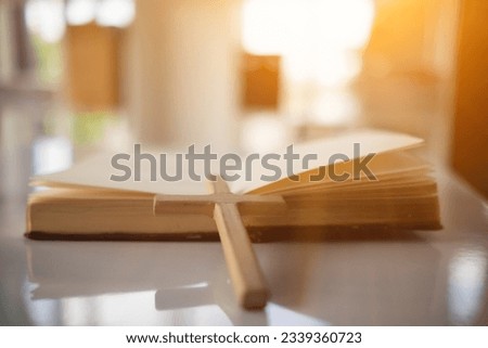 Cross represents God placed on Bible which is teaching of God according to Christian faith. cross and Bible were placed on table in room as they were prepared for prayers to God by faith.
 Royalty-Free Stock Photo #2339360723