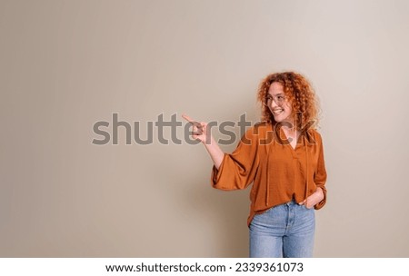 Smiling businesswoman with hand in pocket aiming at copy space for advertisement isolated on background