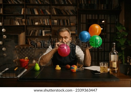 Portrait of senior business man blowing up balloon for success celebration Royalty-Free Stock Photo #2339363447