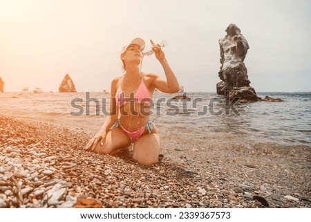 Woman travel sea. Happy tourist in pink bikini enjoy taking picture outdoors for memories. Woman traveler takes photo by sea. Volcanic mountains surround her on beach for adventurous journey.