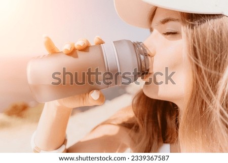 Fintess woman drinking water. Happy, active middle aged woman standing on beach and drinking water after excersise. Concept of lifestyle, sport. Close up