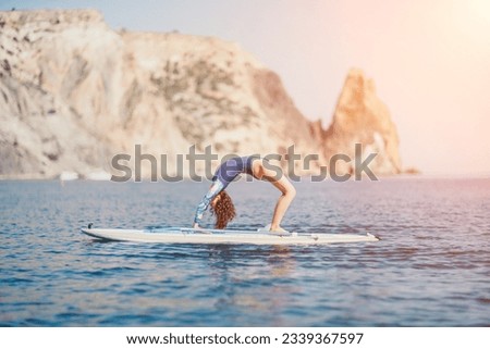 Woman sup yoga. Middle age sporty woman practising yoga pilates on paddle sup surfboard. Female stretching doing workout on sea water. Modern individual female hipster outdoor summer sport activity. Royalty-Free Stock Photo #2339367597