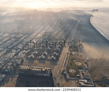 Aerial Picture of similar houses at sunrise with fog alongside beach in Karachi Pakistan