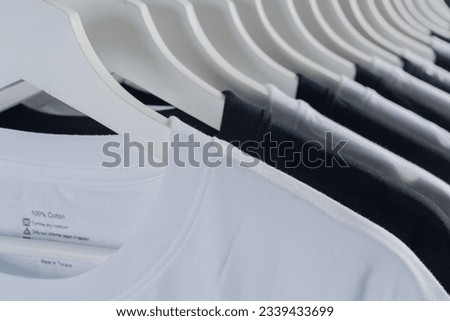 close up collection of black-white and green color t-shirt hanging on wooden clothes hanger, apparel background